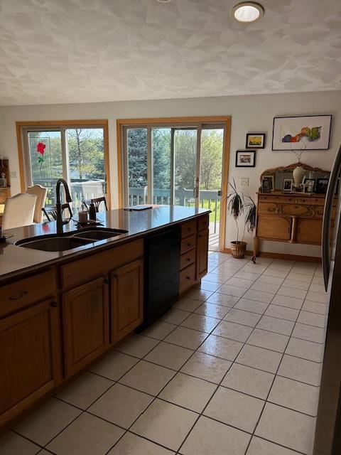 kitchen featuring sink, black appliances, a textured ceiling, and light tile patterned floors