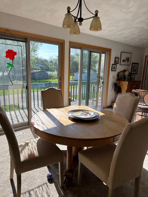 carpeted dining area featuring vaulted ceiling and an inviting chandelier