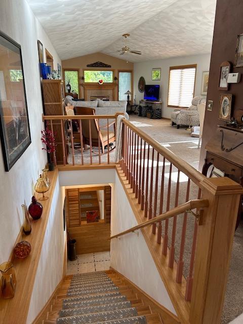 stairs featuring ceiling fan, a textured ceiling, and lofted ceiling