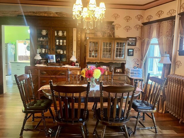 dining area featuring hardwood / wood-style floors, an inviting chandelier, crown molding, and radiator