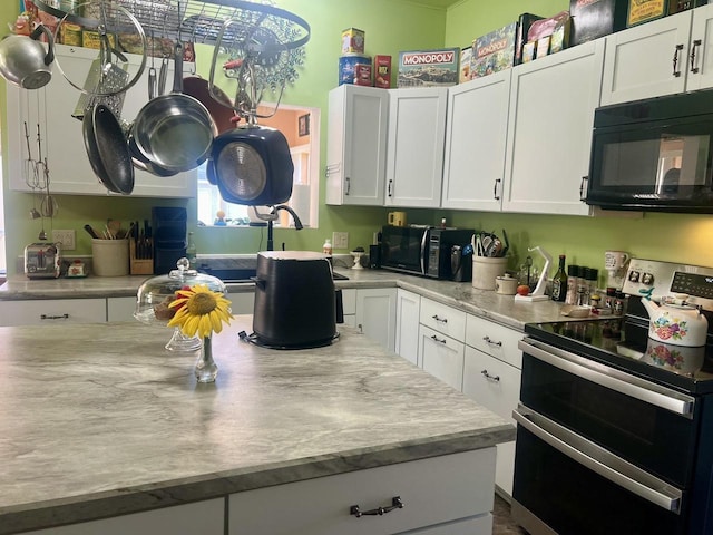 kitchen with white cabinets, light stone countertops, and range with two ovens