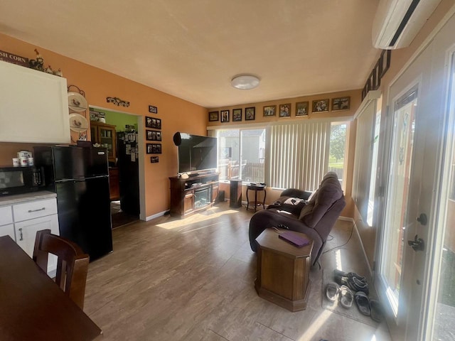 living room with a wall mounted air conditioner and light hardwood / wood-style flooring