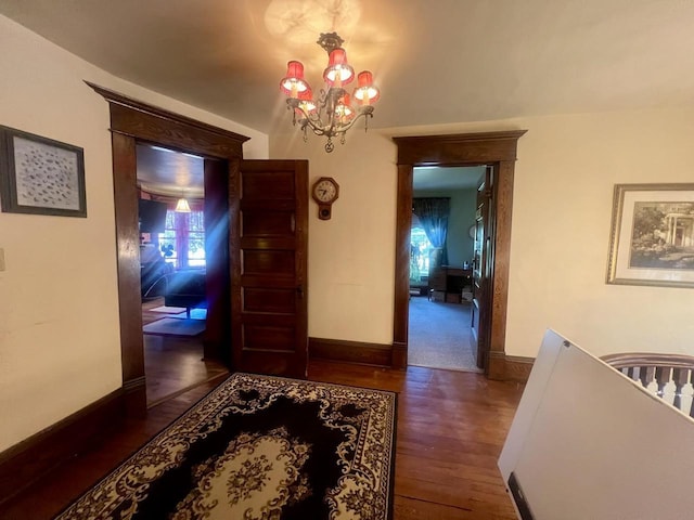 hall with dark hardwood / wood-style flooring and an inviting chandelier