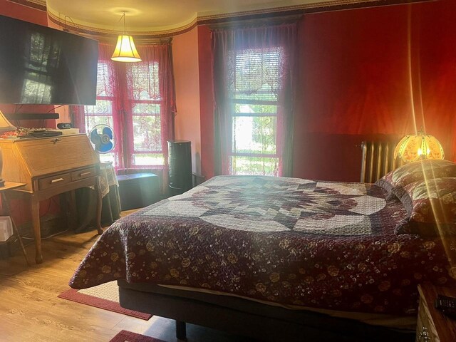 bedroom with ornamental molding and light hardwood / wood-style flooring