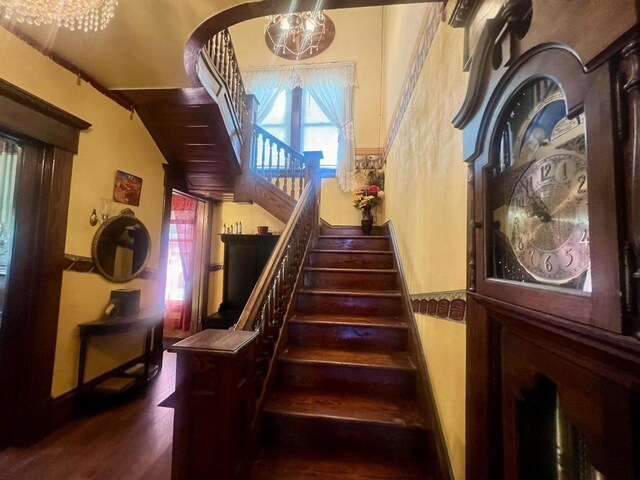 stairs featuring a notable chandelier and wood-type flooring