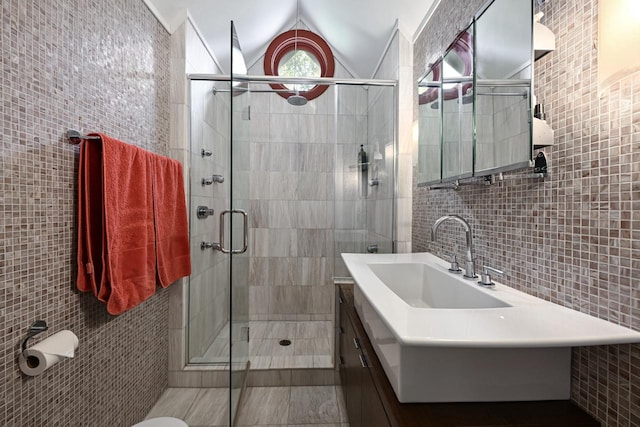 bathroom with tile walls, vaulted ceiling, an enclosed shower, and vanity