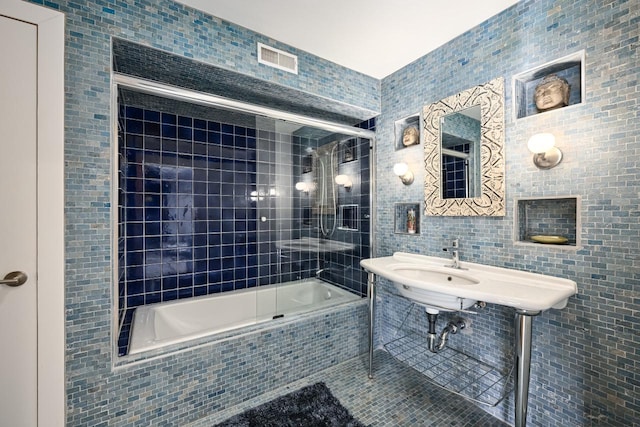 bathroom featuring tiled shower / bath, tile patterned flooring, and tile walls