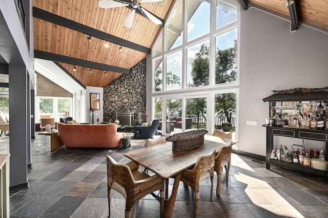 tiled dining room with beam ceiling, high vaulted ceiling, a stone fireplace, and wood ceiling