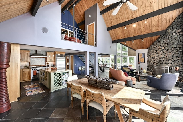 dining space with ceiling fan, beam ceiling, high vaulted ceiling, and a fireplace