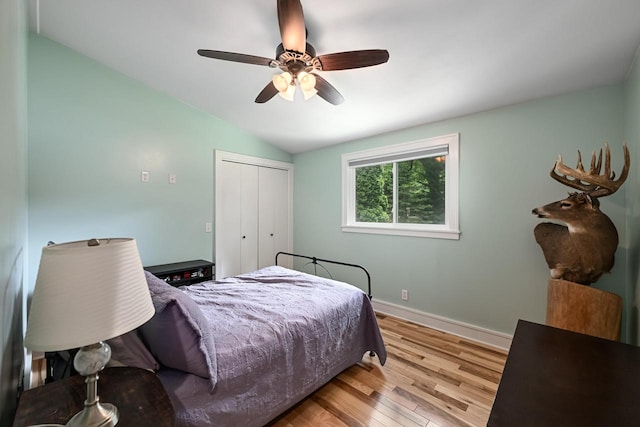 bedroom featuring ceiling fan, a closet, light hardwood / wood-style flooring, and lofted ceiling