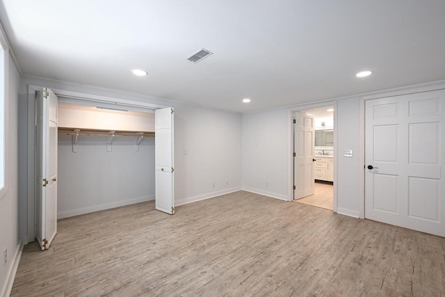 unfurnished bedroom with a closet, connected bathroom, and light hardwood / wood-style flooring