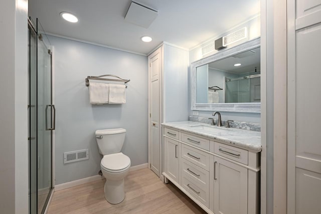 bathroom with an enclosed shower, vanity, hardwood / wood-style floors, and toilet