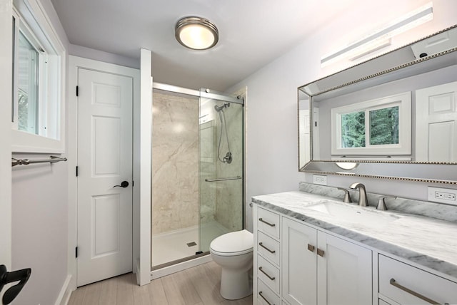 bathroom with hardwood / wood-style flooring, toilet, a shower with shower door, and vanity