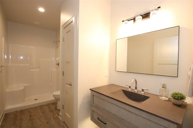 bathroom with vanity, wood finished floors, recessed lighting, walk in shower, and toilet