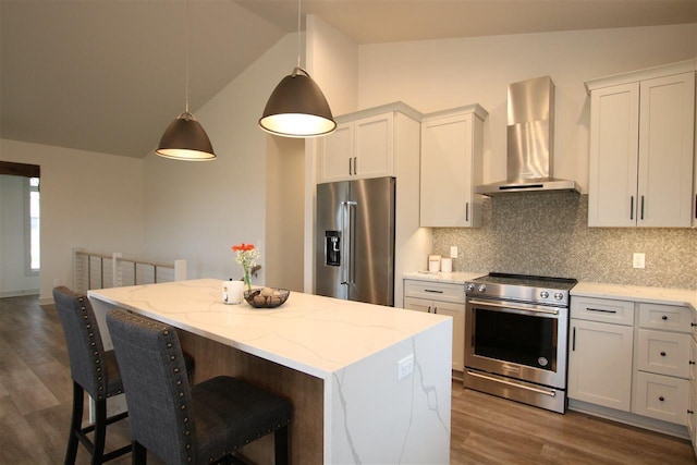 kitchen with lofted ceiling, stainless steel appliances, wall chimney range hood, tasteful backsplash, and a center island