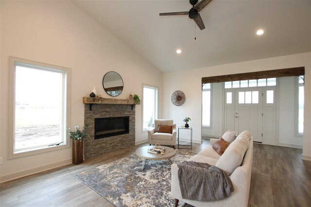 living room with ceiling fan, hardwood / wood-style flooring, plenty of natural light, and a stone fireplace