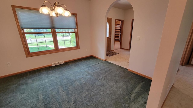 empty room featuring carpet and a chandelier