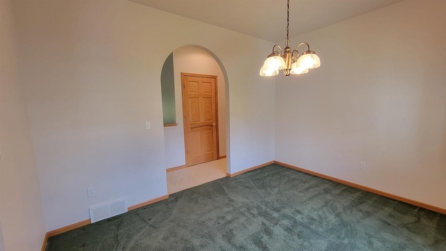 empty room featuring carpet floors and a chandelier