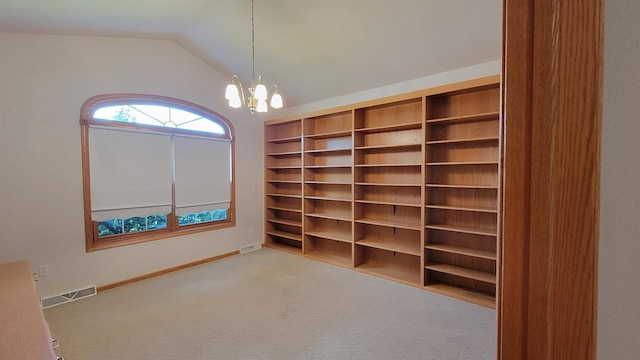 spacious closet with a notable chandelier, light colored carpet, and lofted ceiling