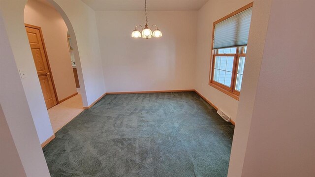 carpeted spare room with an inviting chandelier