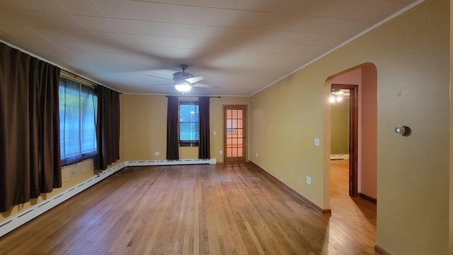 spare room with baseboards, arched walkways, light wood-style flooring, ceiling fan, and crown molding