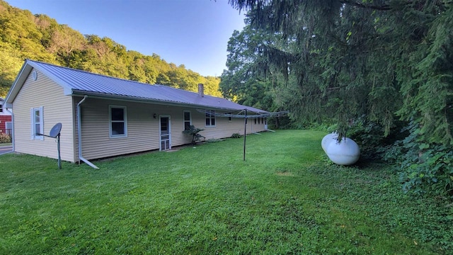 back of property featuring metal roof and a lawn