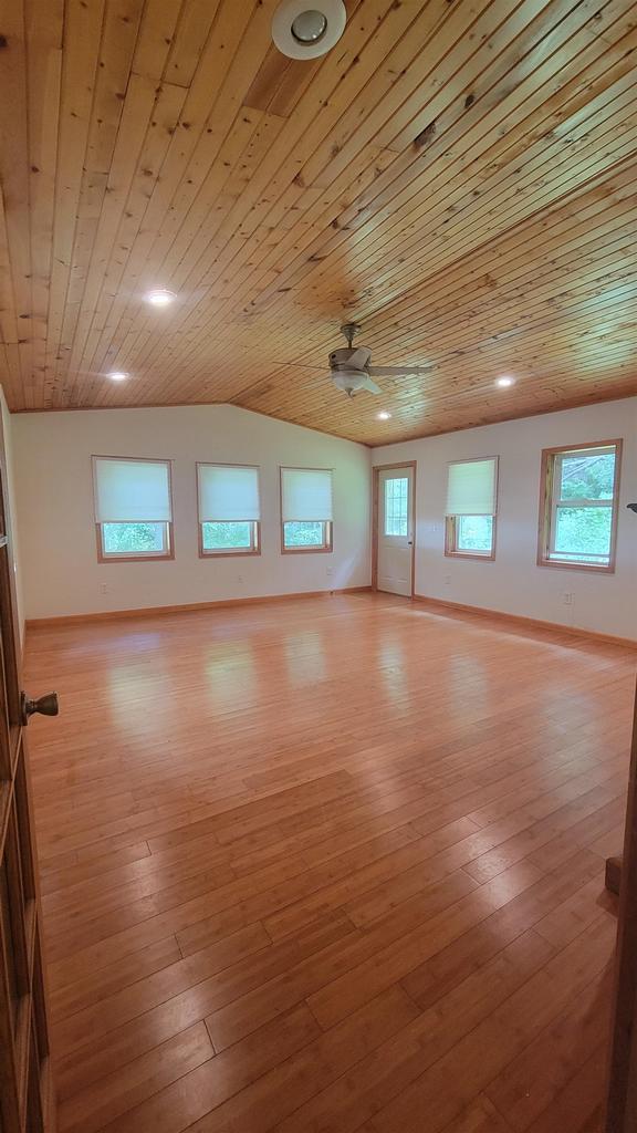 spare room featuring light wood-type flooring, wood ceiling, baseboards, and vaulted ceiling