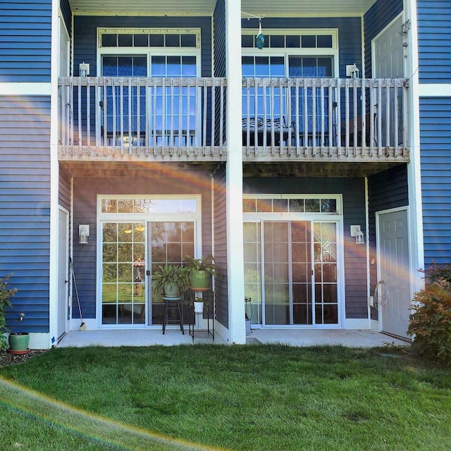 back of house featuring a balcony and a lawn