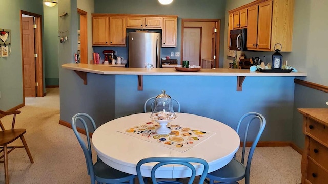 kitchen with a breakfast bar area, kitchen peninsula, and stainless steel fridge