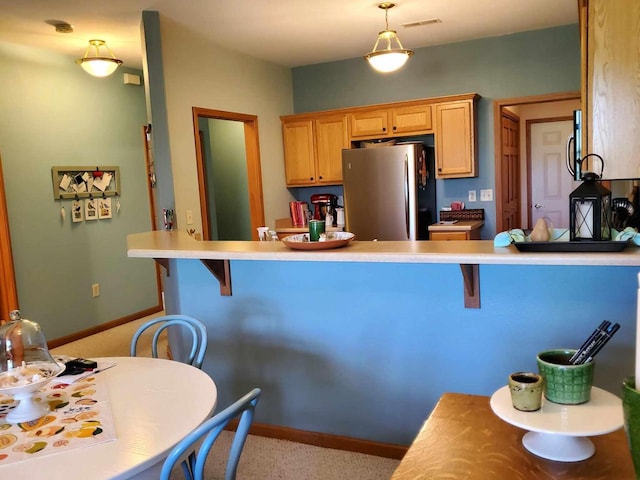 kitchen featuring stainless steel fridge, kitchen peninsula, a breakfast bar area, and light carpet