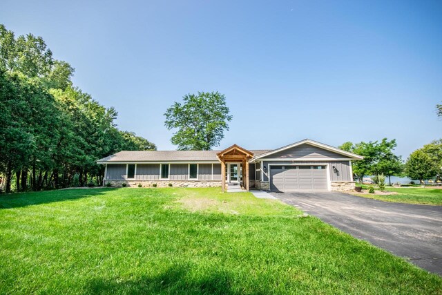 ranch-style house featuring a front lawn, a garage, and a water view