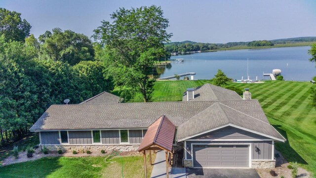 view of front of property with a front lawn, a garage, and a water view