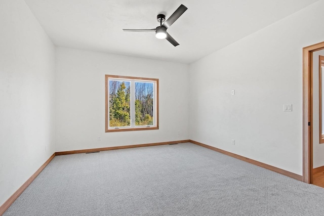 carpeted empty room with a ceiling fan and baseboards