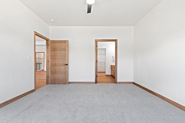 unfurnished bedroom featuring light carpet, a ceiling fan, baseboards, and connected bathroom