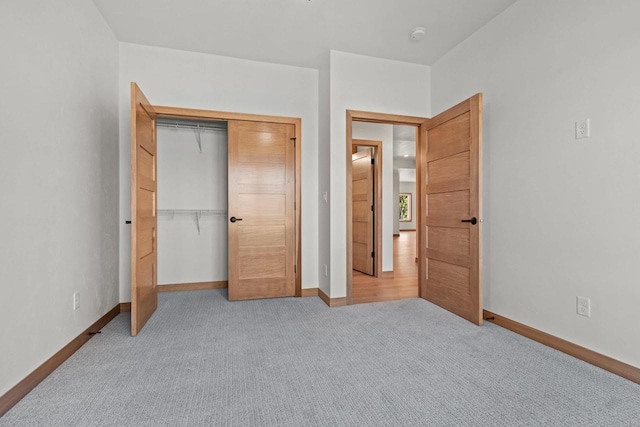 unfurnished bedroom with light carpet, baseboards, and a closet