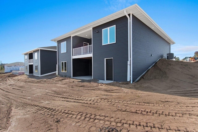 back of house featuring a balcony and central AC unit