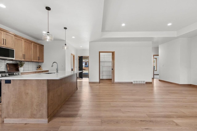 kitchen featuring decorative light fixtures, stainless steel appliances, light countertops, visible vents, and a sink