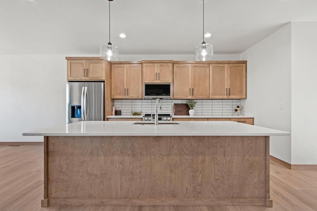 kitchen featuring stainless steel appliances, light countertops, tasteful backsplash, a center island with sink, and pendant lighting