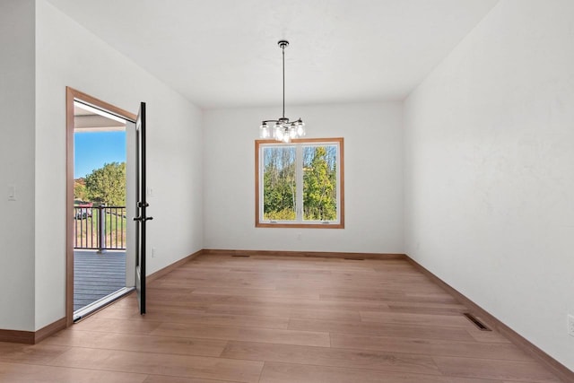 unfurnished dining area with light wood-style flooring, plenty of natural light, visible vents, and an inviting chandelier