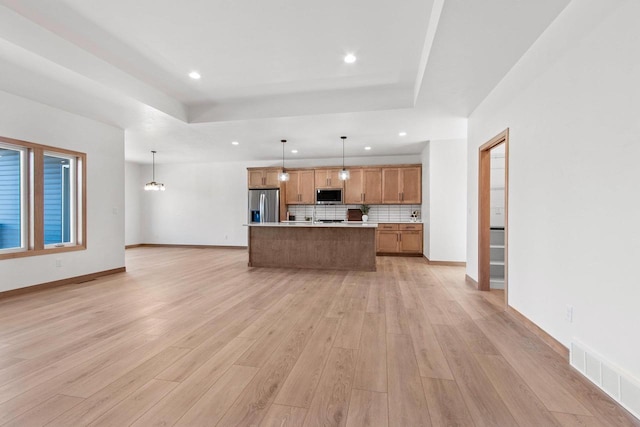 kitchen featuring visible vents, hanging light fixtures, appliances with stainless steel finishes, light countertops, and a tray ceiling