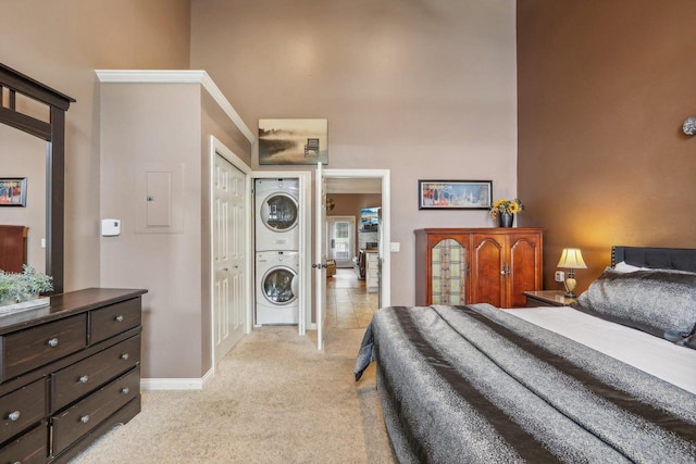 carpeted bedroom with a towering ceiling and stacked washing maching and dryer