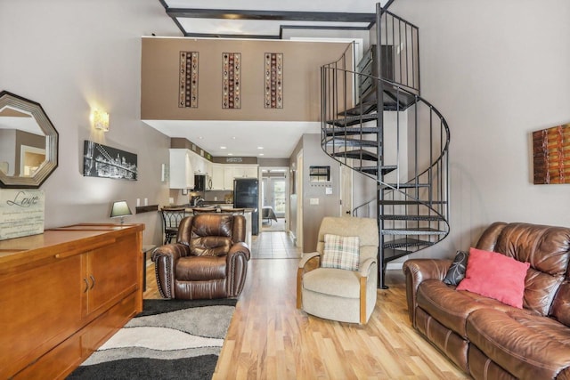 living room with light wood finished floors, stairway, and a towering ceiling