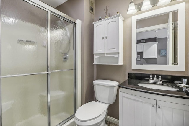 bathroom with toilet, vanity, a shower stall, and visible vents