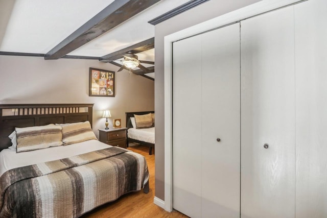 bedroom featuring lofted ceiling with beams, ceiling fan, a closet, and light wood-style flooring