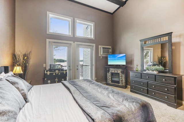 bedroom with carpet floors, a high ceiling, a fireplace, access to exterior, and an AC wall unit