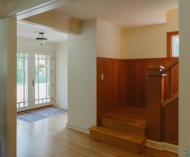 stairs with french doors and hardwood / wood-style floors