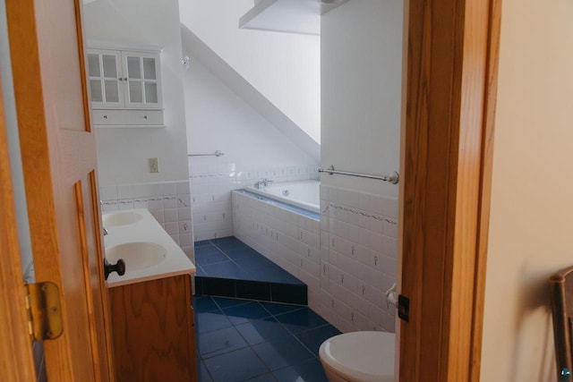 bathroom featuring tiled bath, toilet, vanity, tile walls, and tile patterned floors