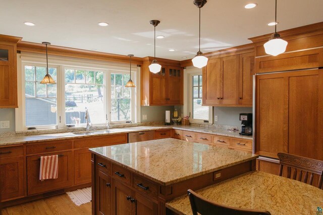 kitchen featuring light hardwood / wood-style flooring, hanging light fixtures, paneled built in refrigerator, light stone counters, and sink