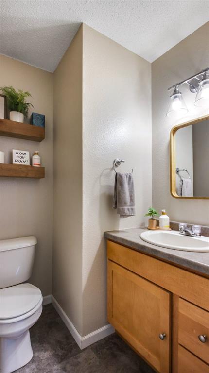 bathroom with tile patterned floors, a textured ceiling, vanity, and toilet