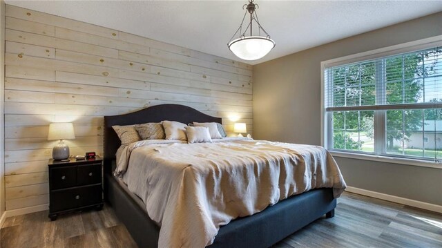 bedroom with wood walls and dark hardwood / wood-style floors